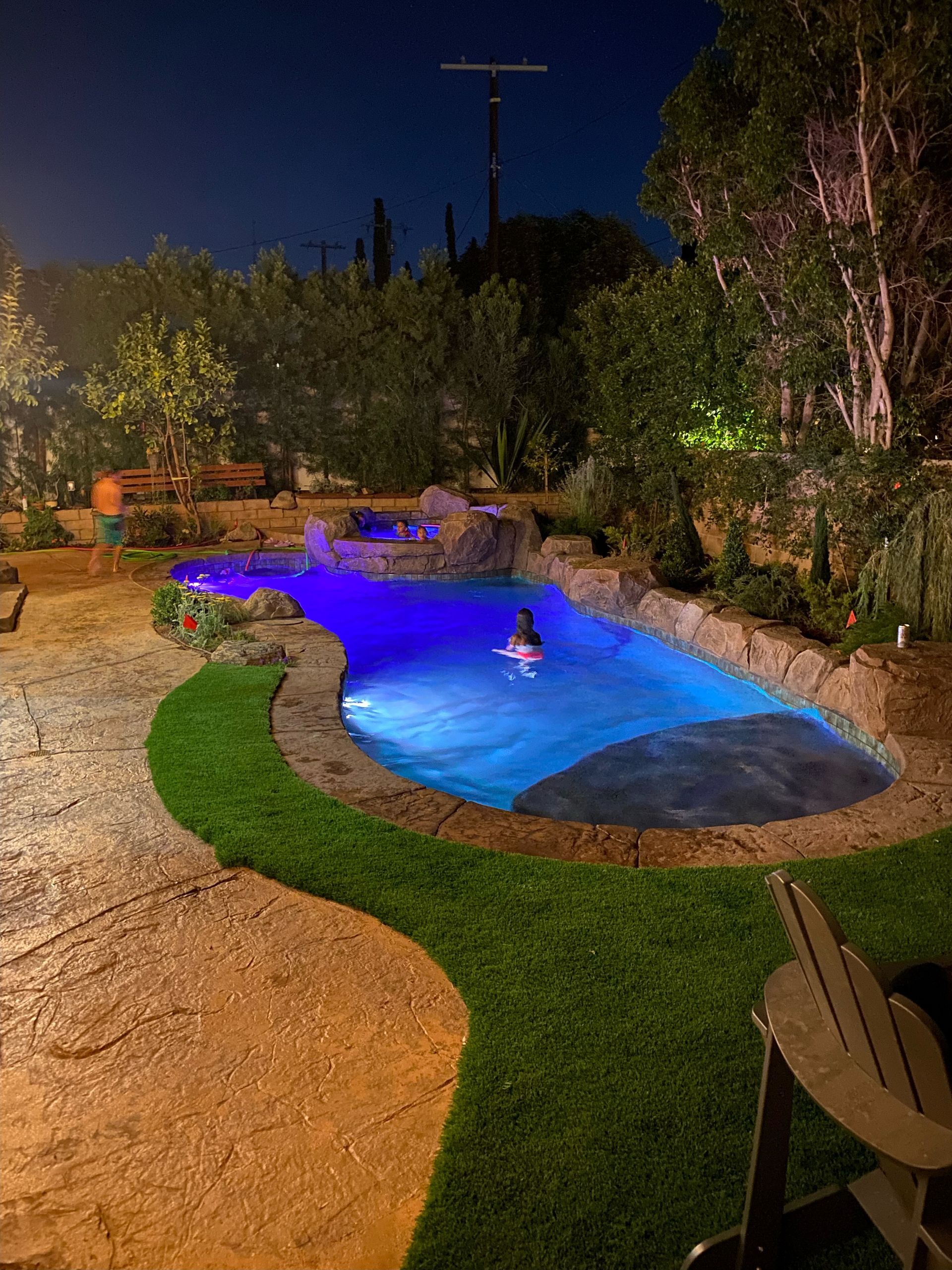 A person is swimming in a swimming pool at night.