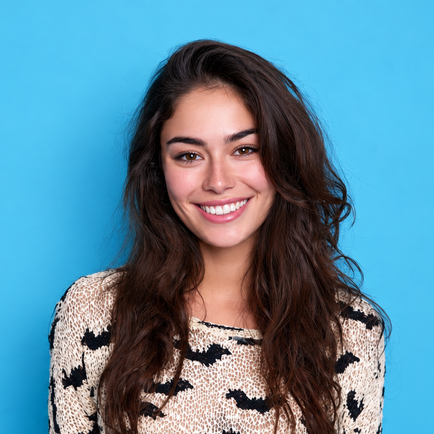 Smiling woman with dark hair in a cream patterned sweater against a blue background