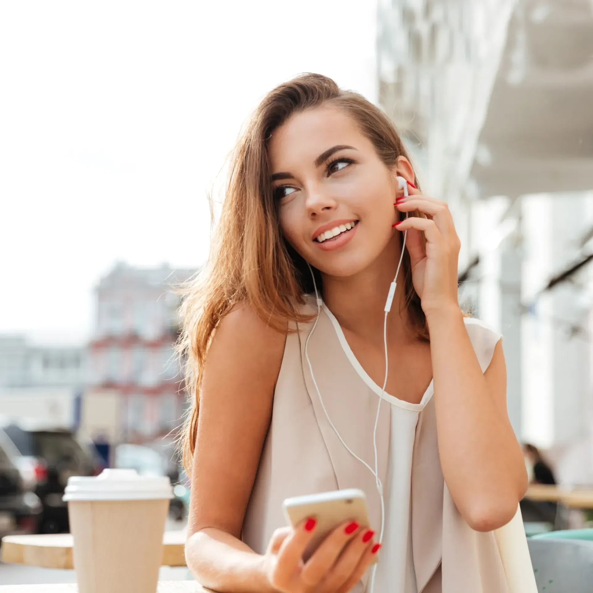Woman sitting outside with coffee and headphones in