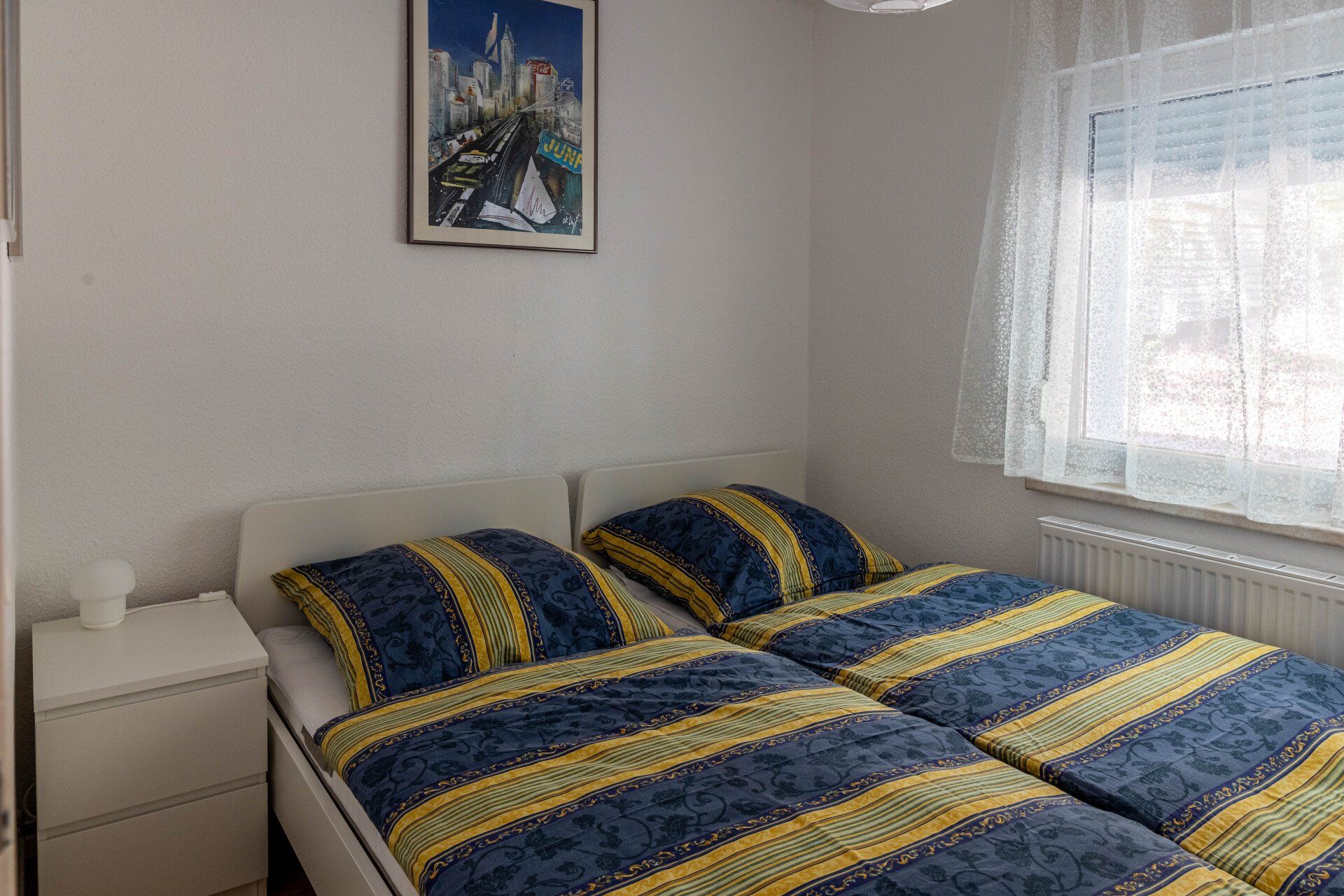 Ein Schlafzimmer mit zwei Betten und einem Bild an der Wand.