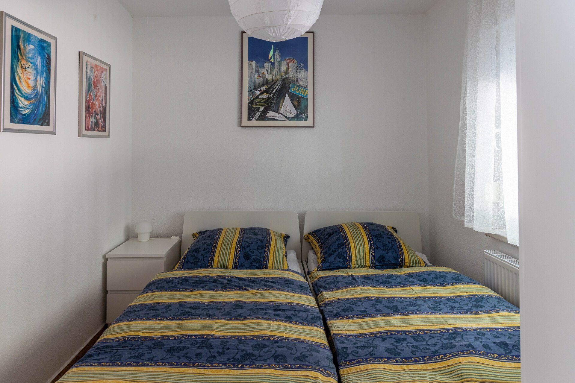 Ein Schlafzimmer mit zwei Betten, einem Nachttisch und einem Fenster.