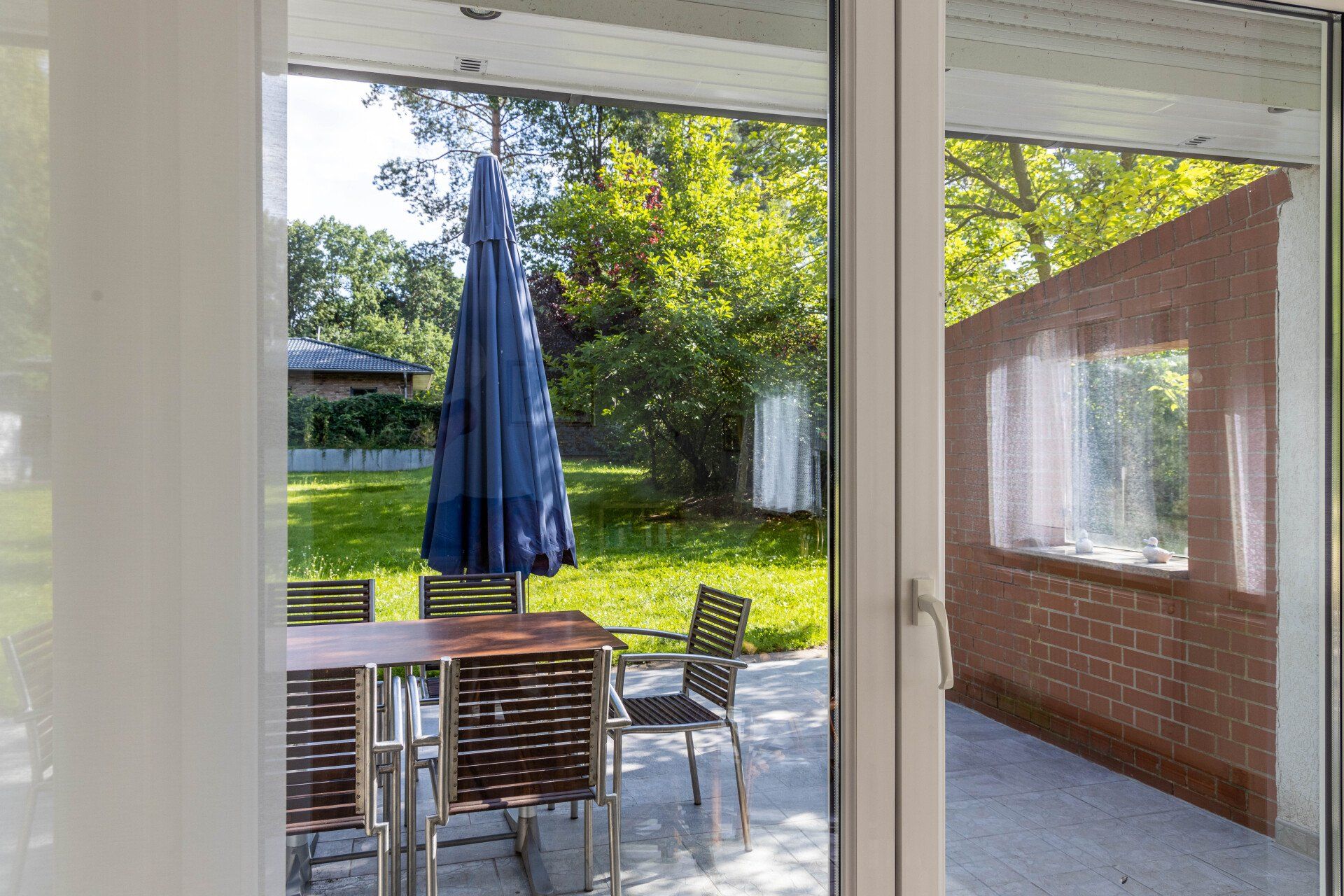 Eine Terrasse mit Tisch, Stühlen und Sonnenschirm.