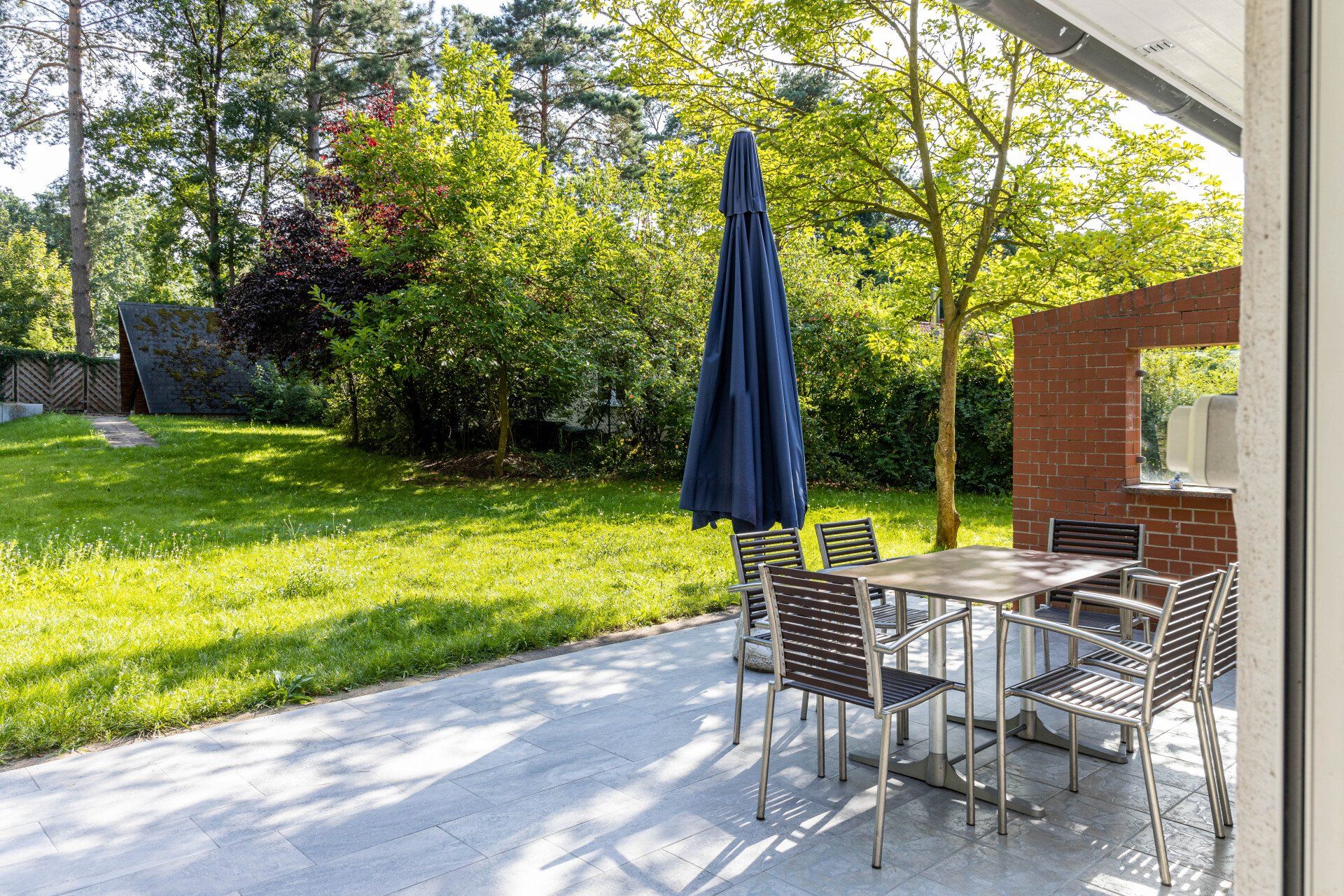 Eine Terrasse mit Tisch, Stühlen und Sonnenschirm.