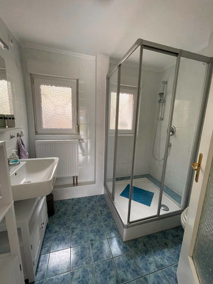 Ein Badezimmer mit Waschbecken, Dusche und Fenster.
