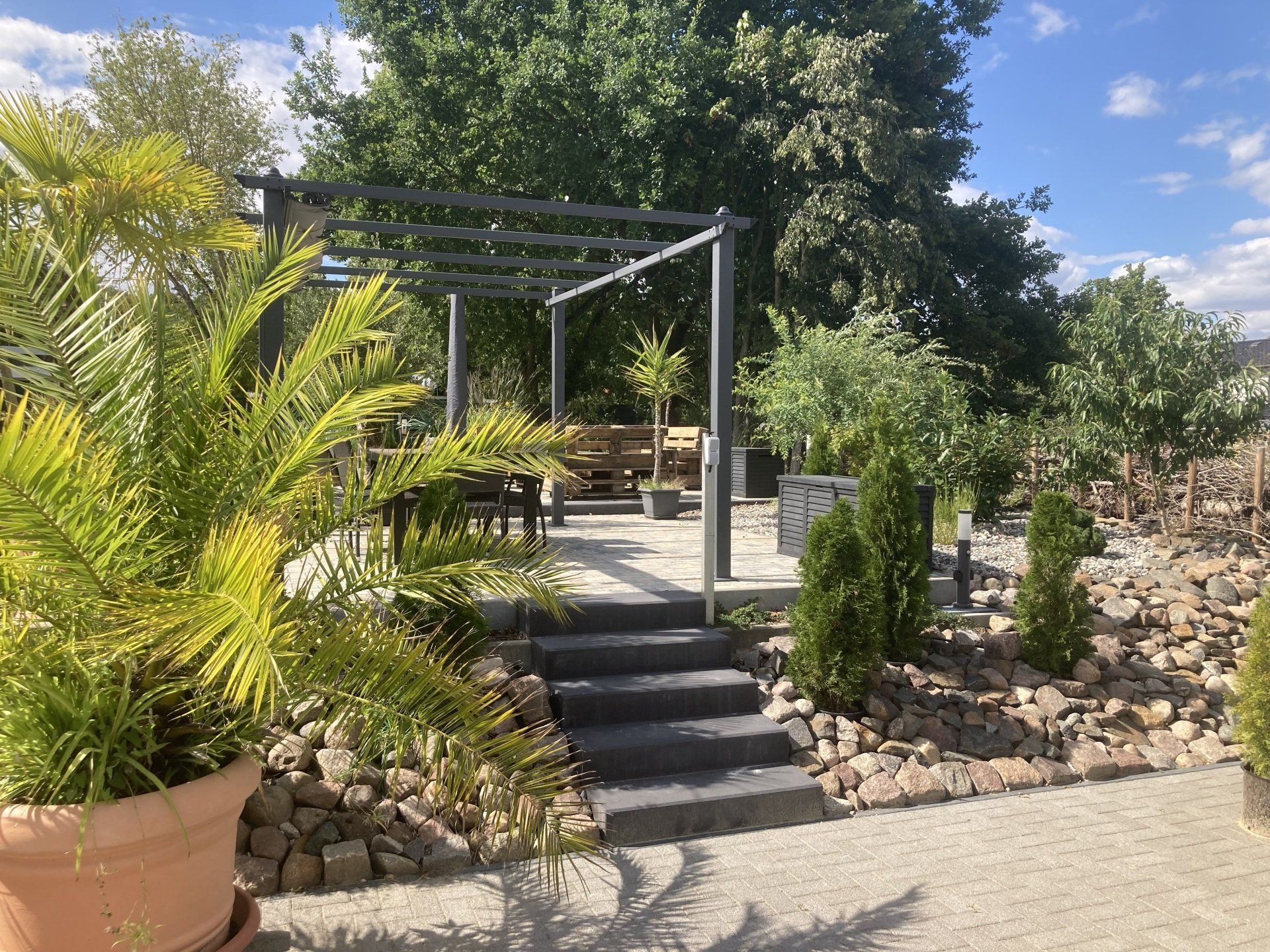 Ein üppiger grüner Garten mit einer Pergola und einer Treppe, die dorthin führt.
