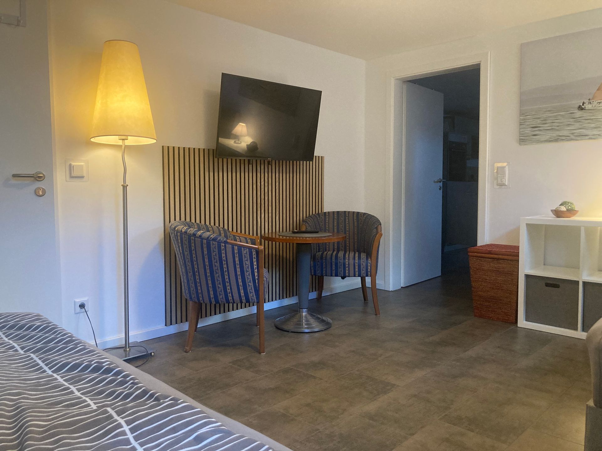 Ein Wohnzimmer mit Bett, Stühlen, Tisch und Fernseher.