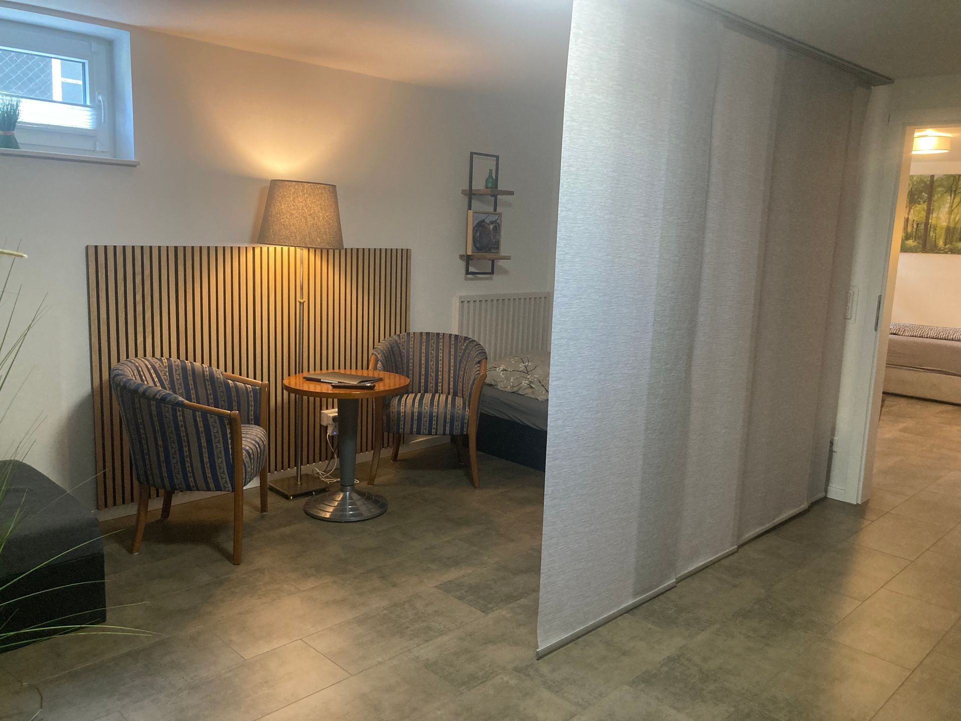 Ein Wohnzimmer mit Stühlen, einem Tisch und einer Lampe.