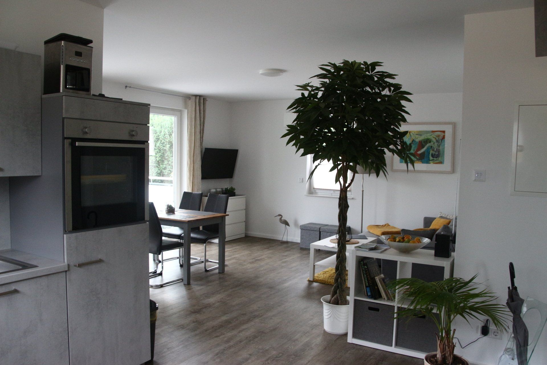 Ein Wohnzimmer mit einem Tisch, Stühlen und einer Topfpflanze.