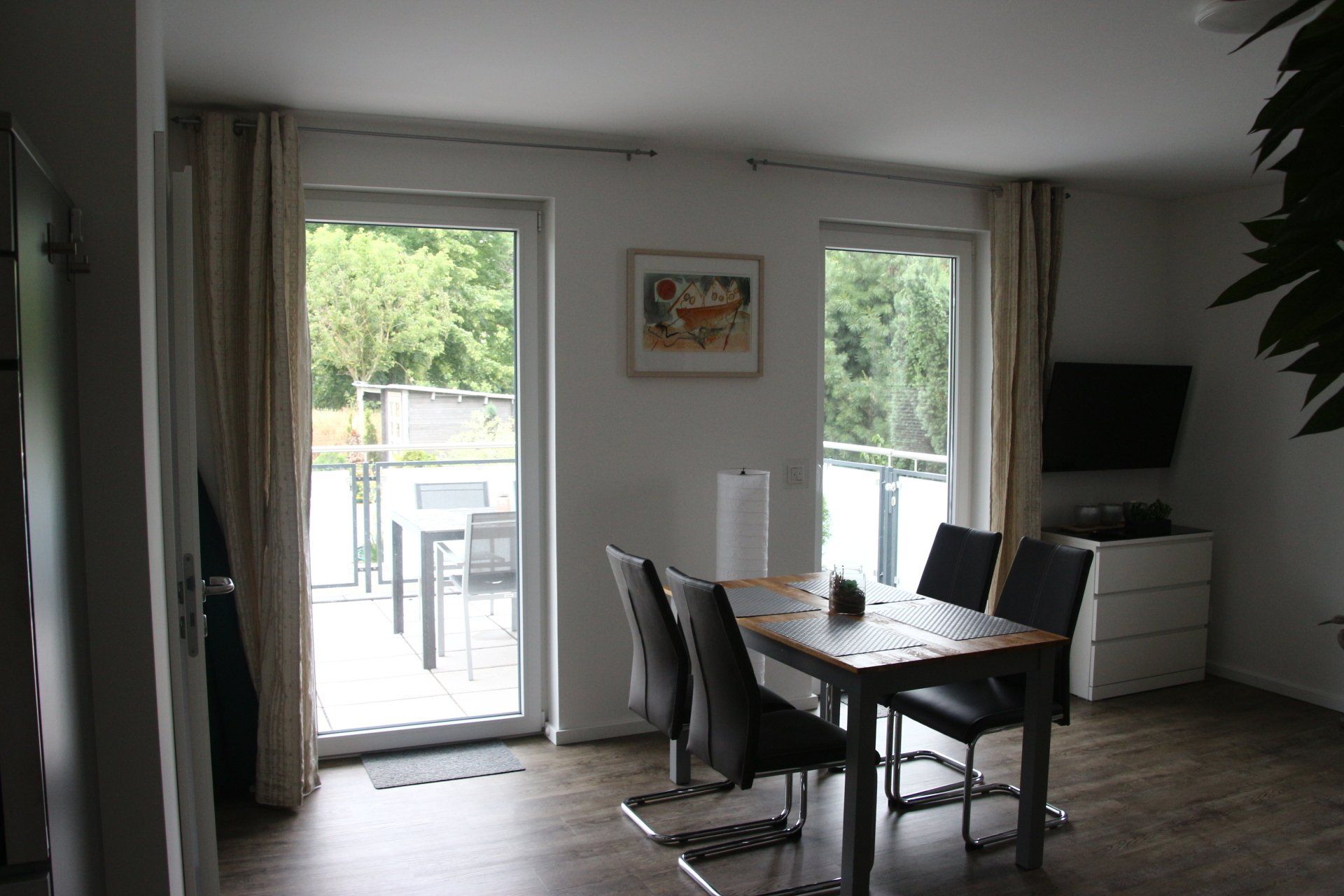 Ein Wohnzimmer mit Esstisch und Stühlen und ein Balkon.