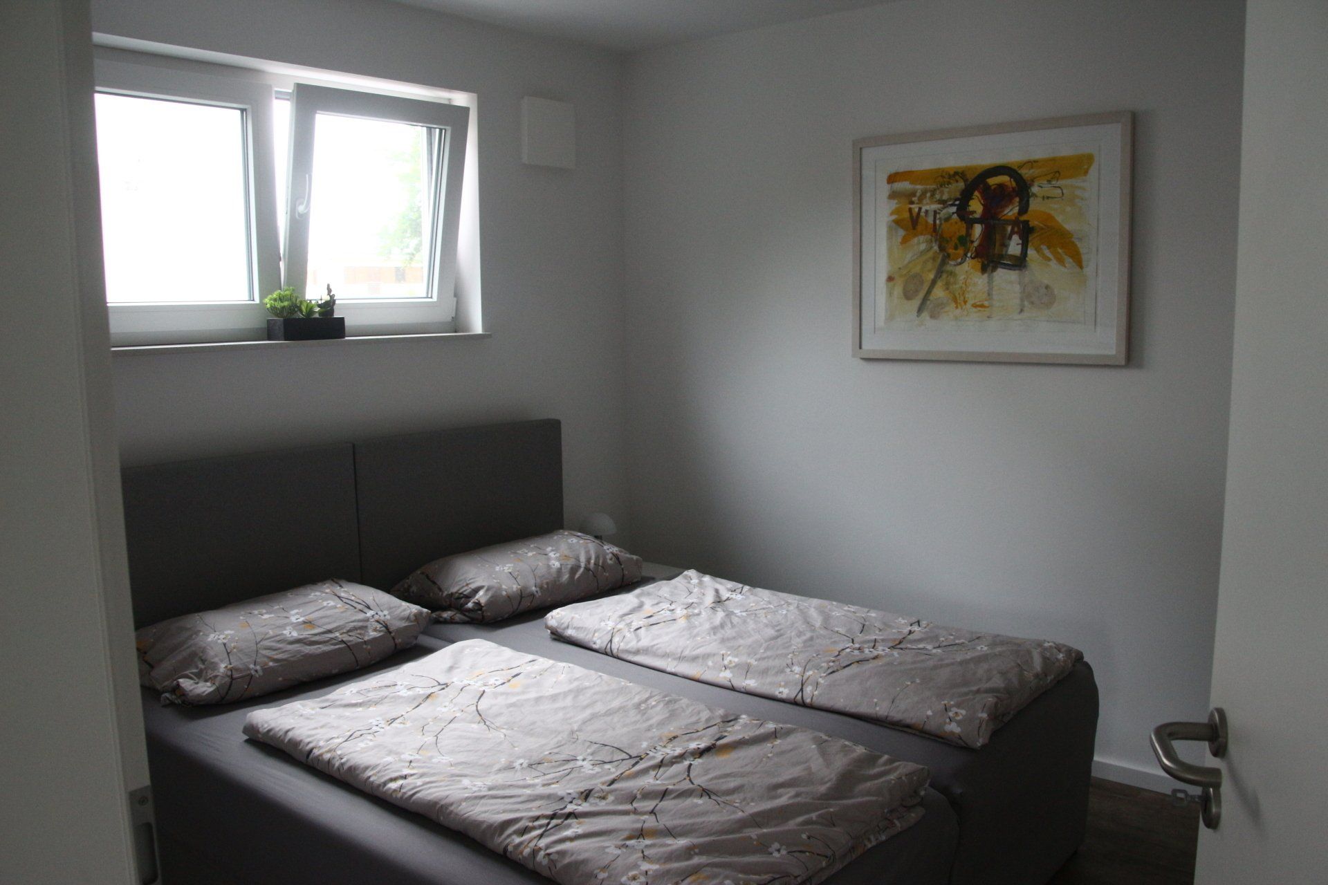 Ein Schlafzimmer mit zwei Betten und einem Bild an der Wand.
