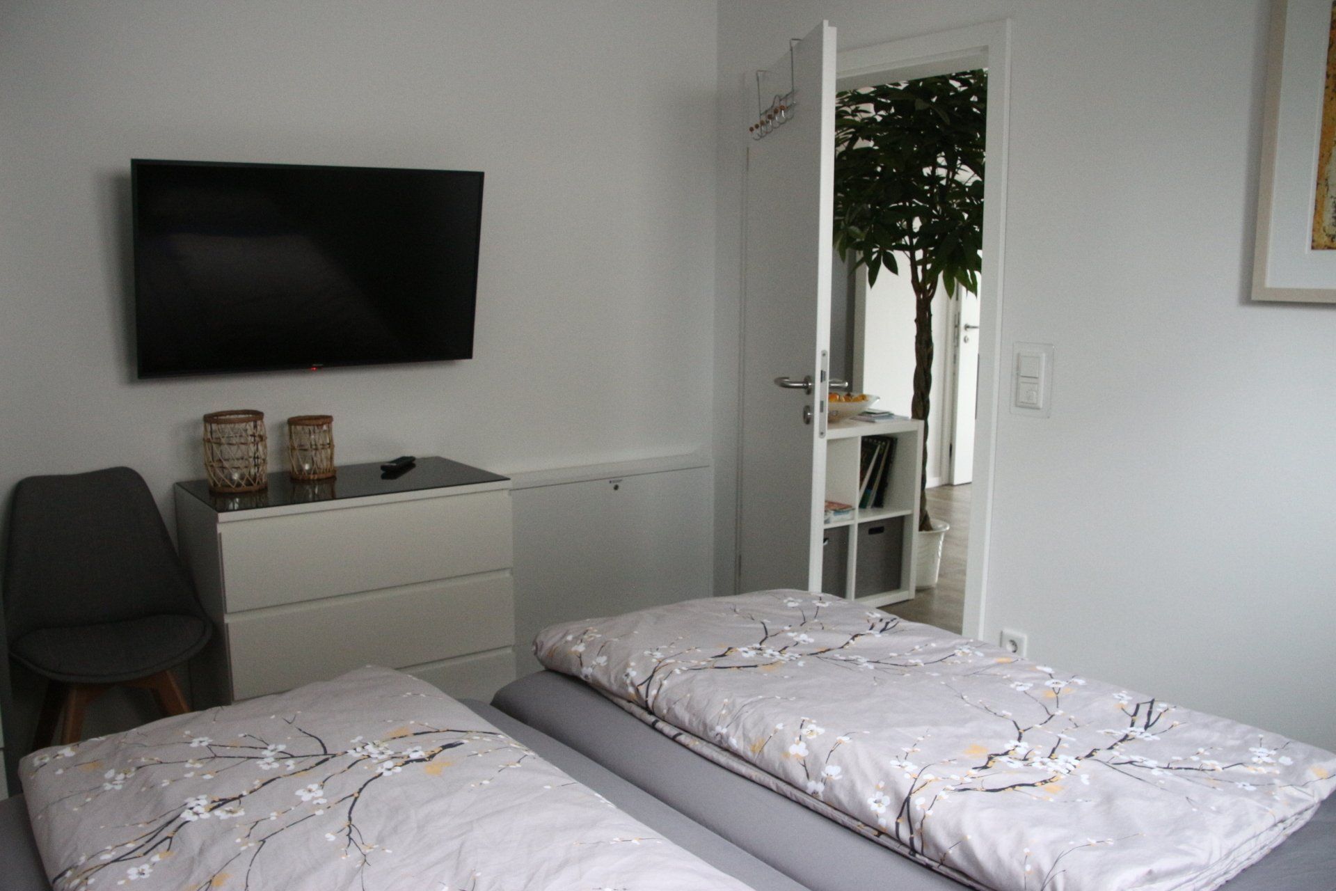 Ein Schlafzimmer mit Bett, Kommode, Fernseher und Spiegel.