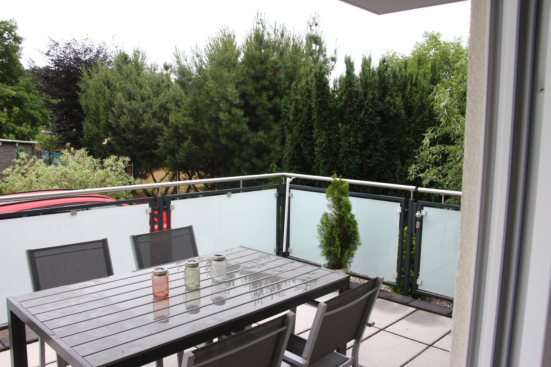 Ein Tisch und Stühle auf einem Balkon mit Bäumen im Hintergrund