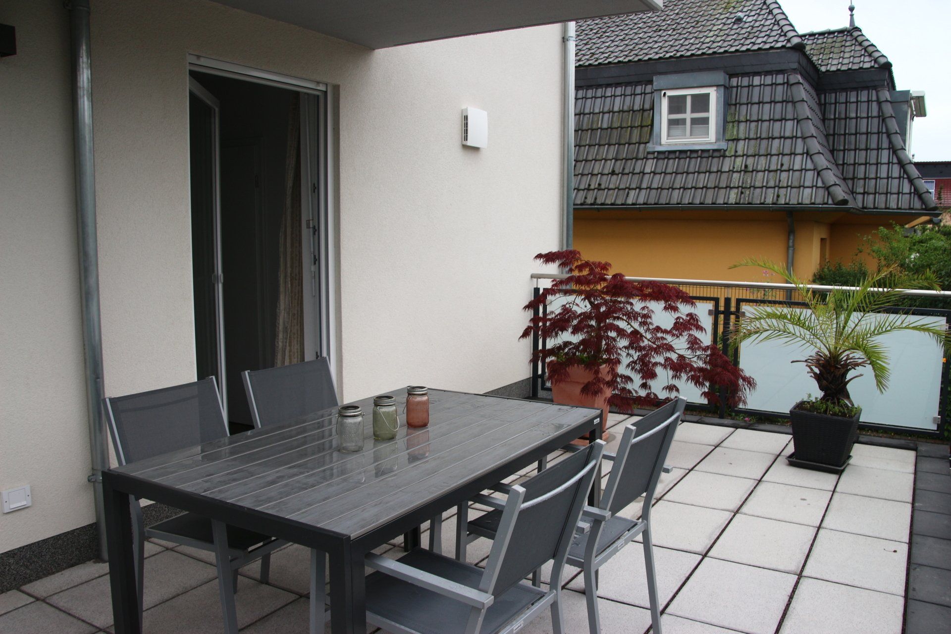 Ein Tisch und Stühle auf einem Balkon mit einem Haus im Hintergrund