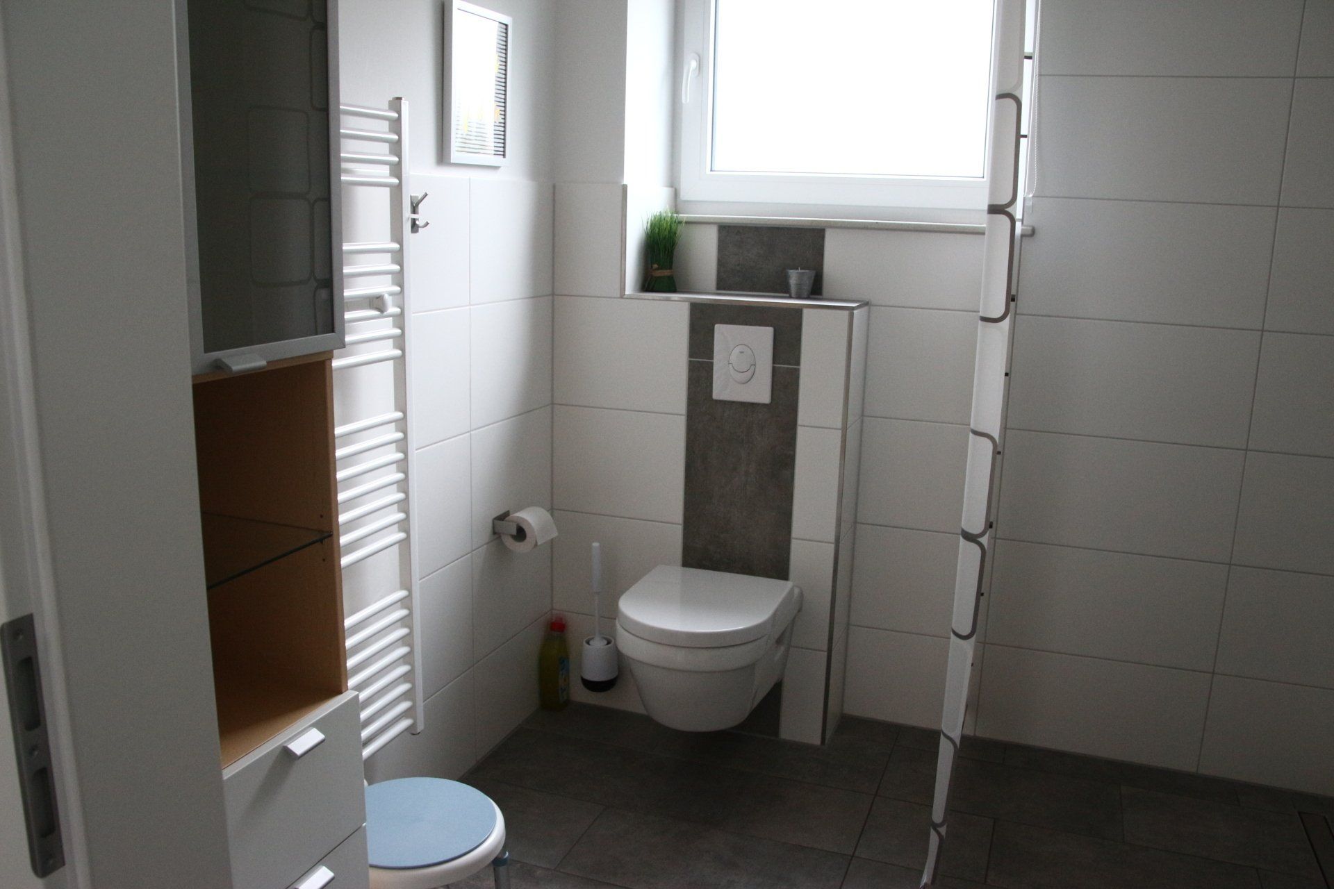 Ein Badezimmer mit Toilette, Handtuchhalter, Spiegel und Fenster.
