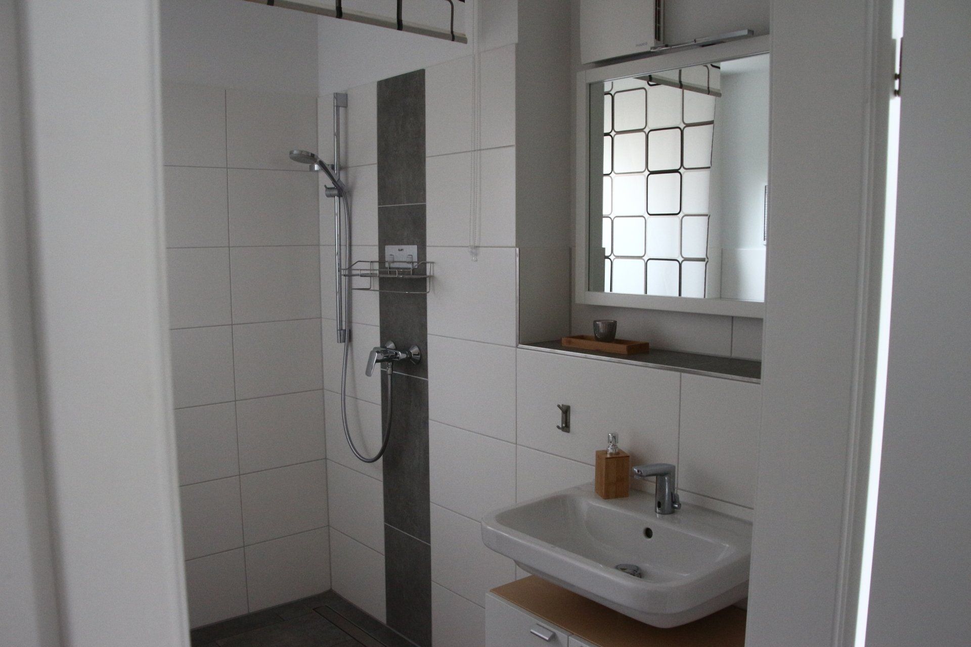 Ein Badezimmer mit Waschbecken, Spiegel und Dusche.
