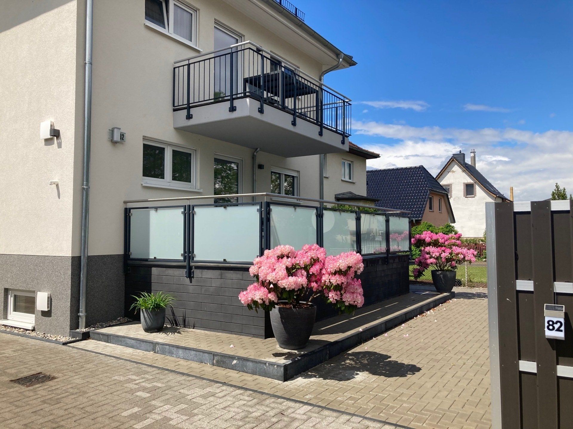 Ein weißes Haus mit einem Balkon und rosa Blumen davor