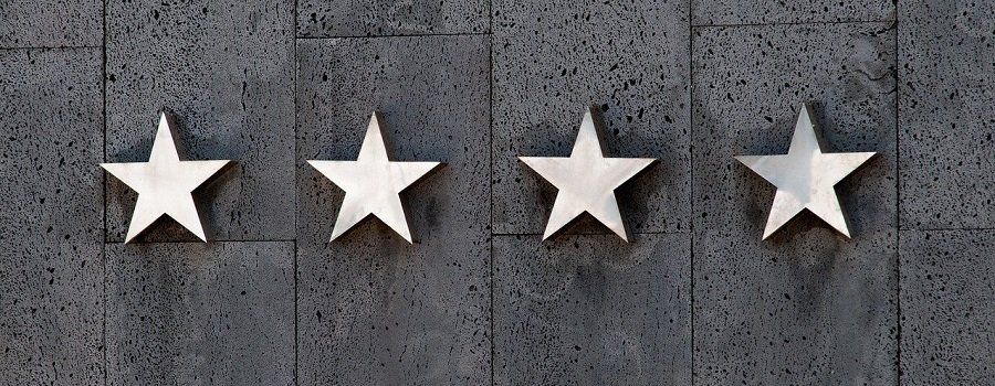 Auf einer Backsteinmauer sind vier Sterne aufgereiht.