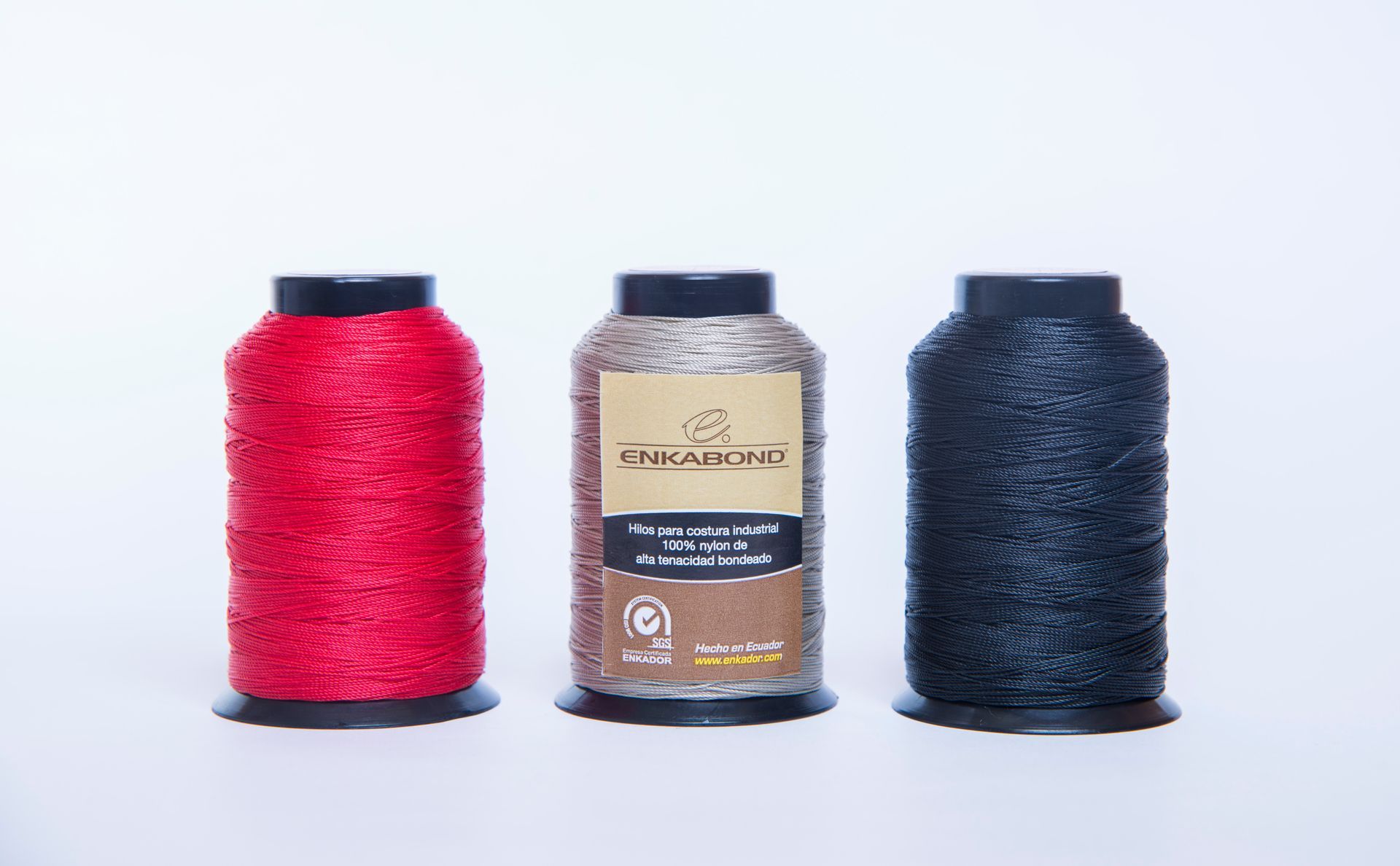 Three spools of textured thread: red, beige, and dark blue on a white background.
