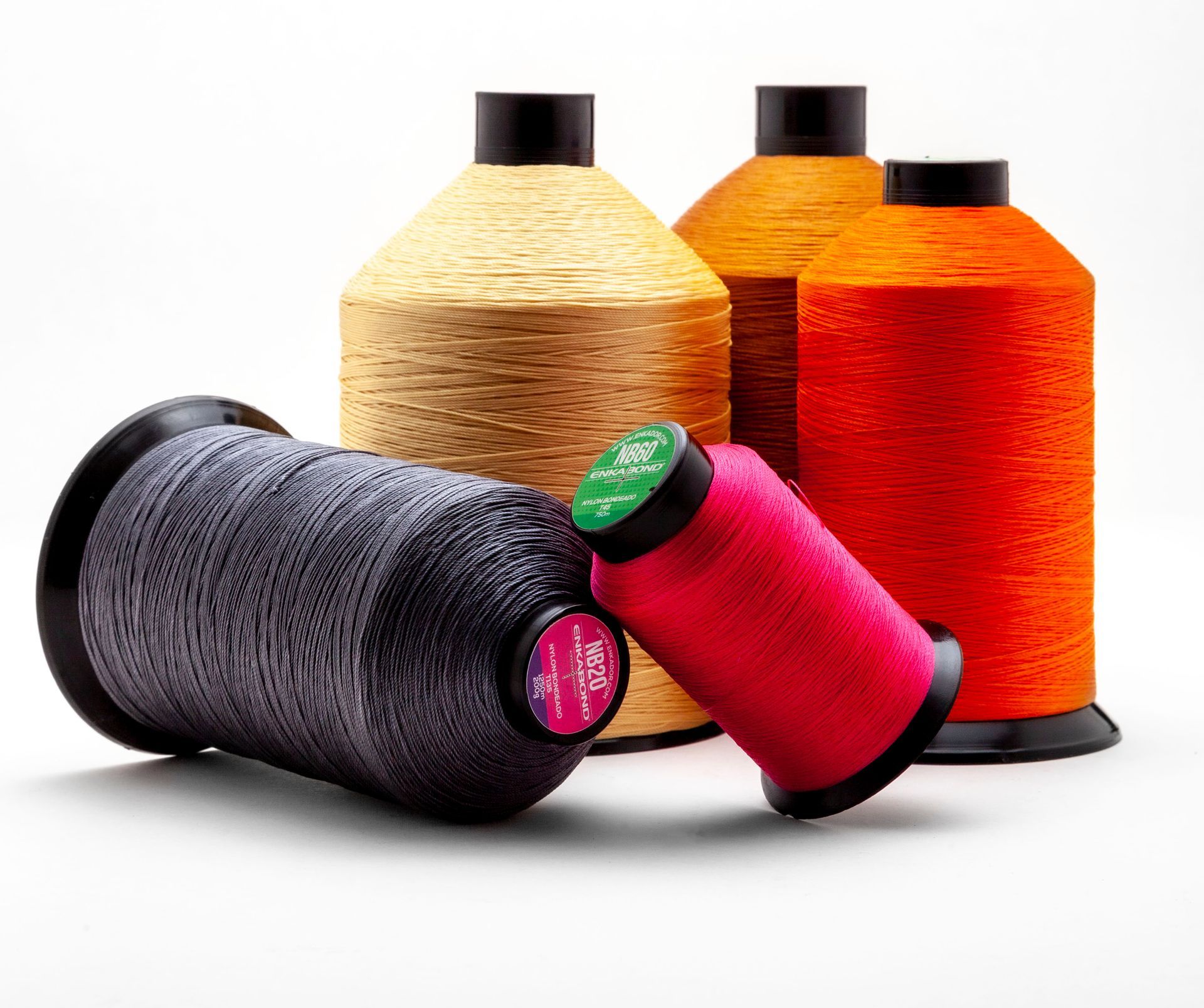 Assorted colorful spools of thread in orange, gold, black, and pink on a white background