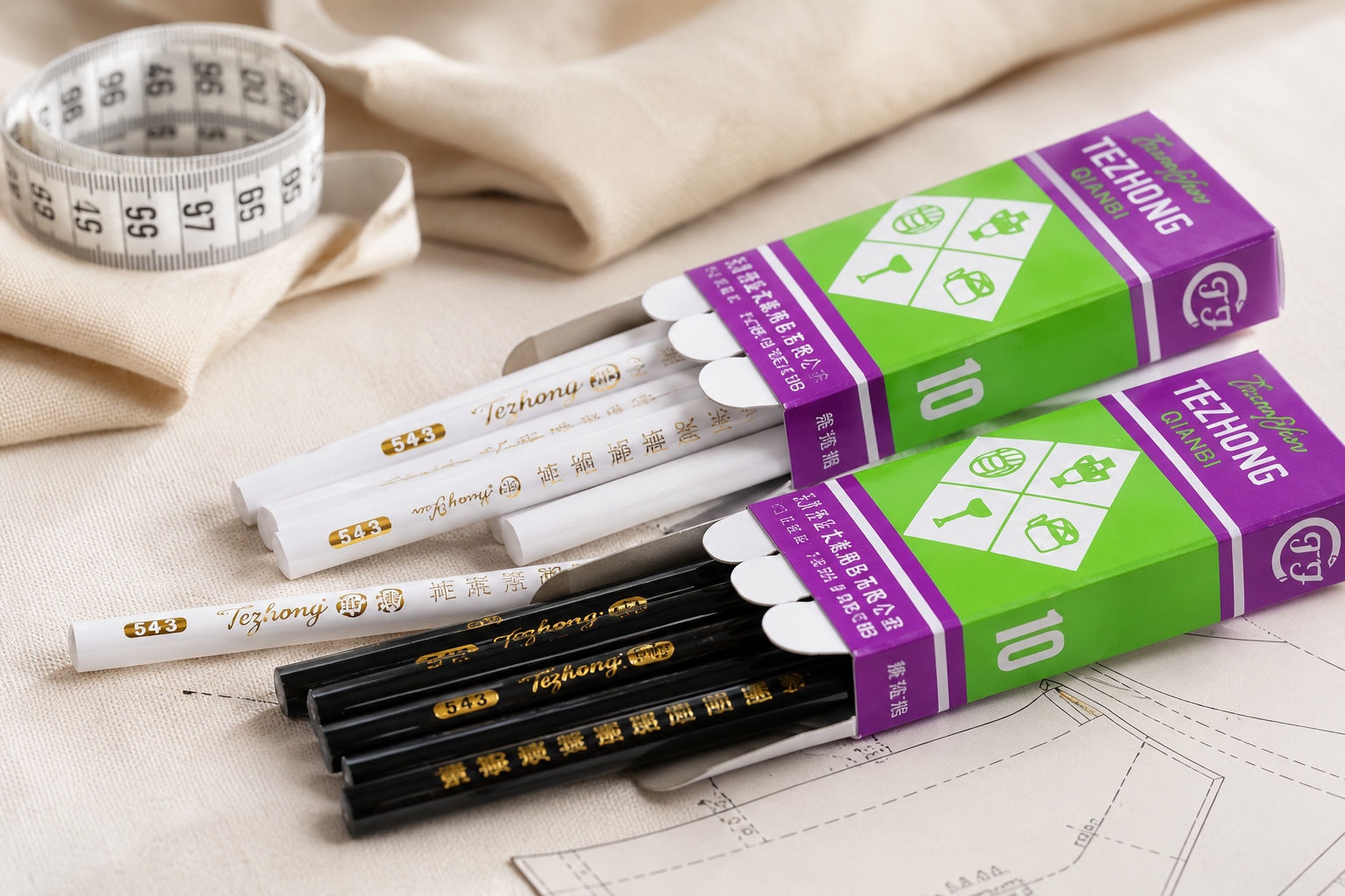 White and black wooden pencils in purple and green packaging on a beige fabric background