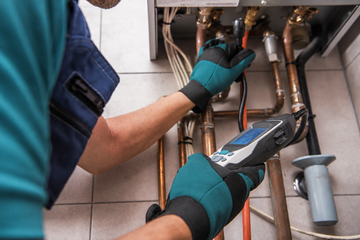 Technician using a wrench to repair plumbing pipes under a sink