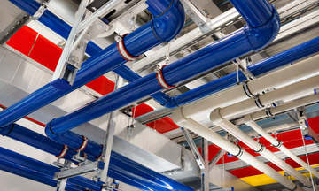 Ceiling pipes and ducts in blue, white, and red in an industrial building interior