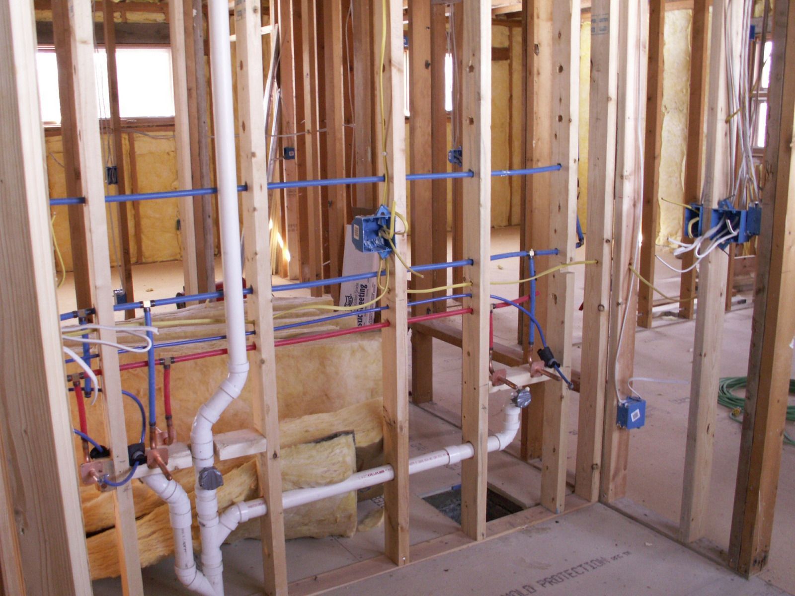 Under-sink plumbing with white PVC pipes, valves, and a drain line inside a cabinet