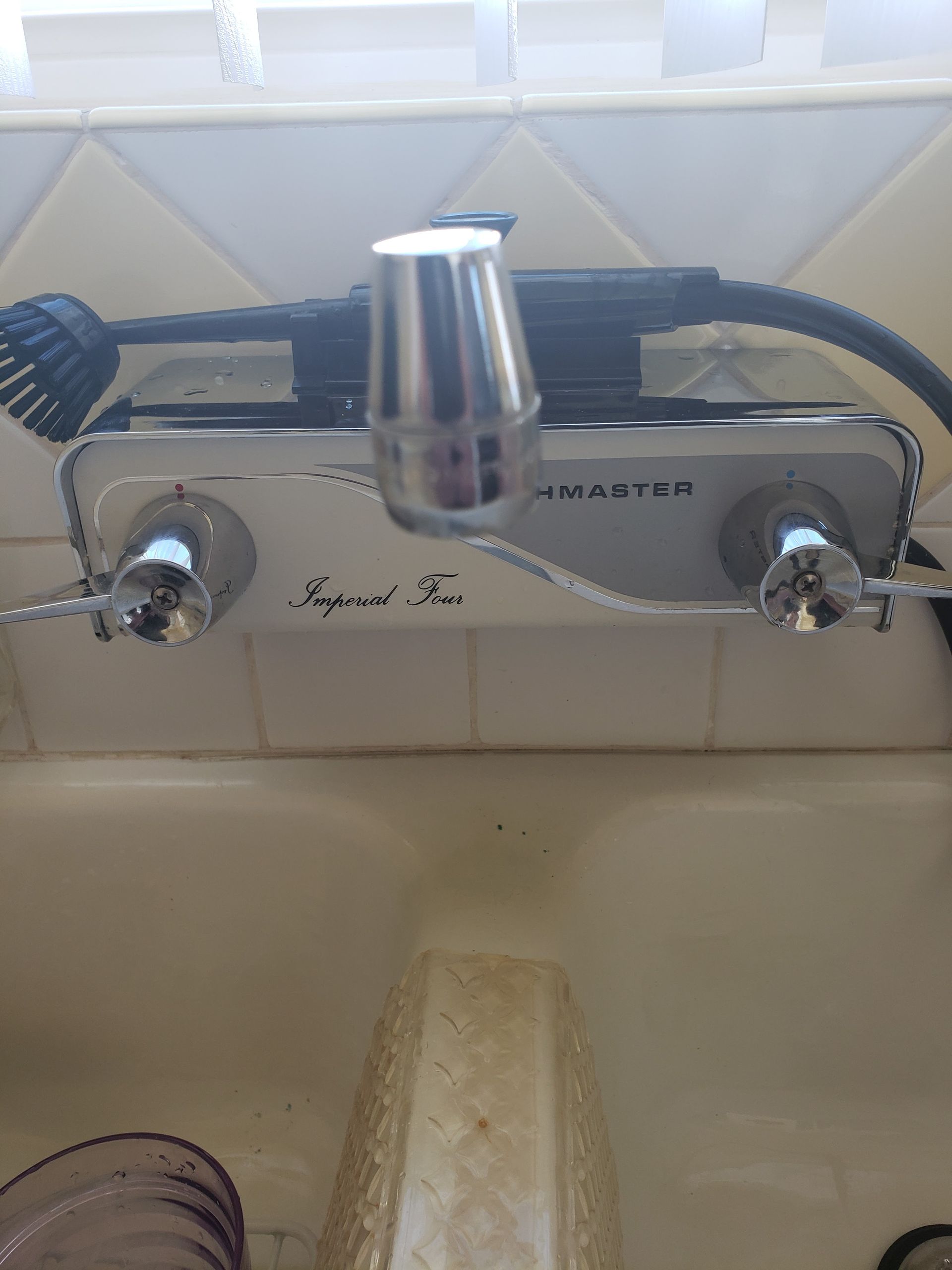 Chrome bathroom faucet with two knobs and a high central spout over a sink.