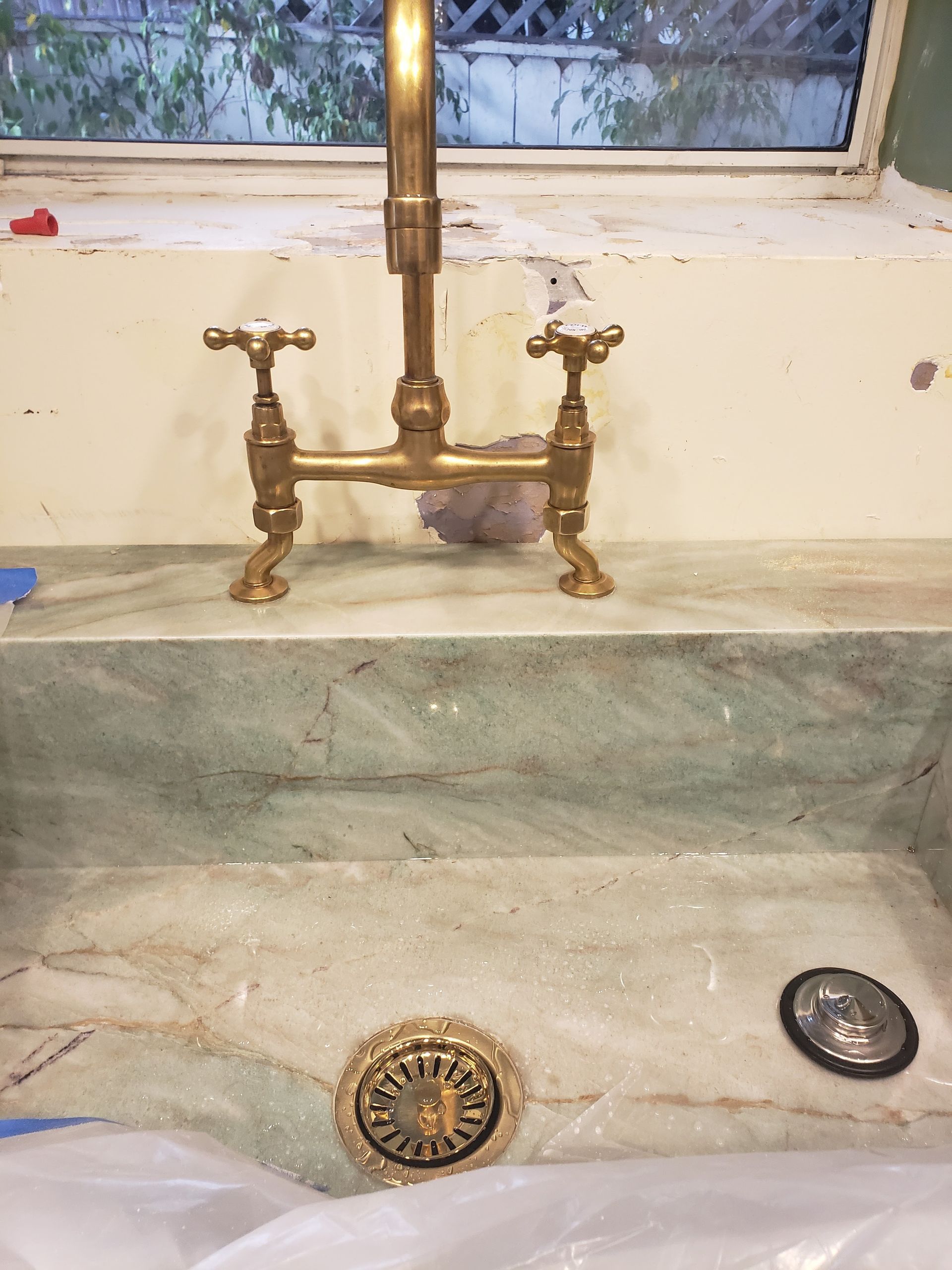 Bathroom sink with brass faucet and exposed drain, set below a small window.