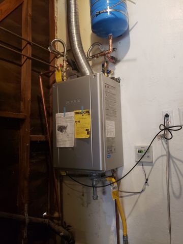 Water heater with blue expansion tank and pipes mounted on a basement wall