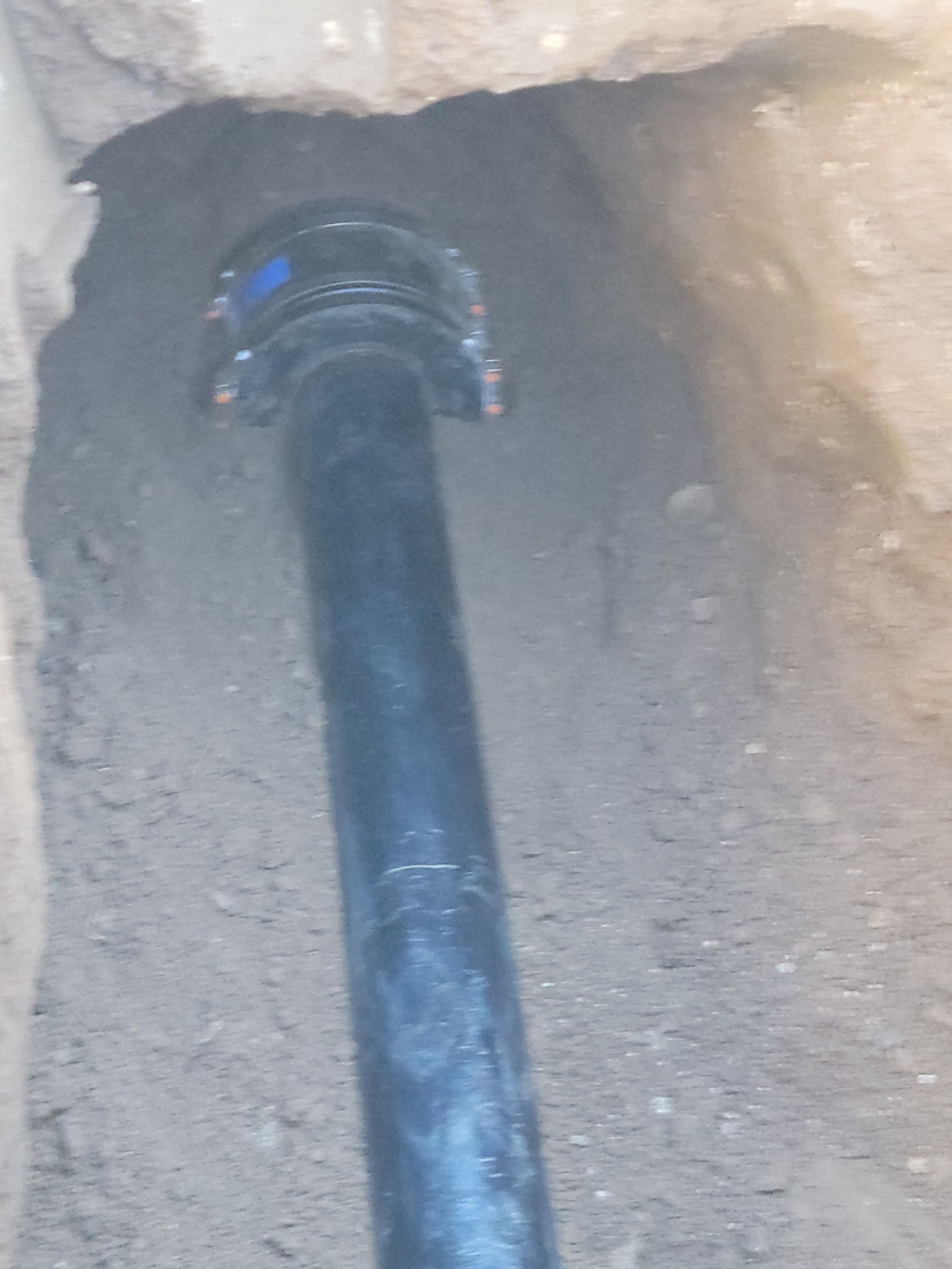 Black pipe entering a hole in a concrete wall with gray sealant around it