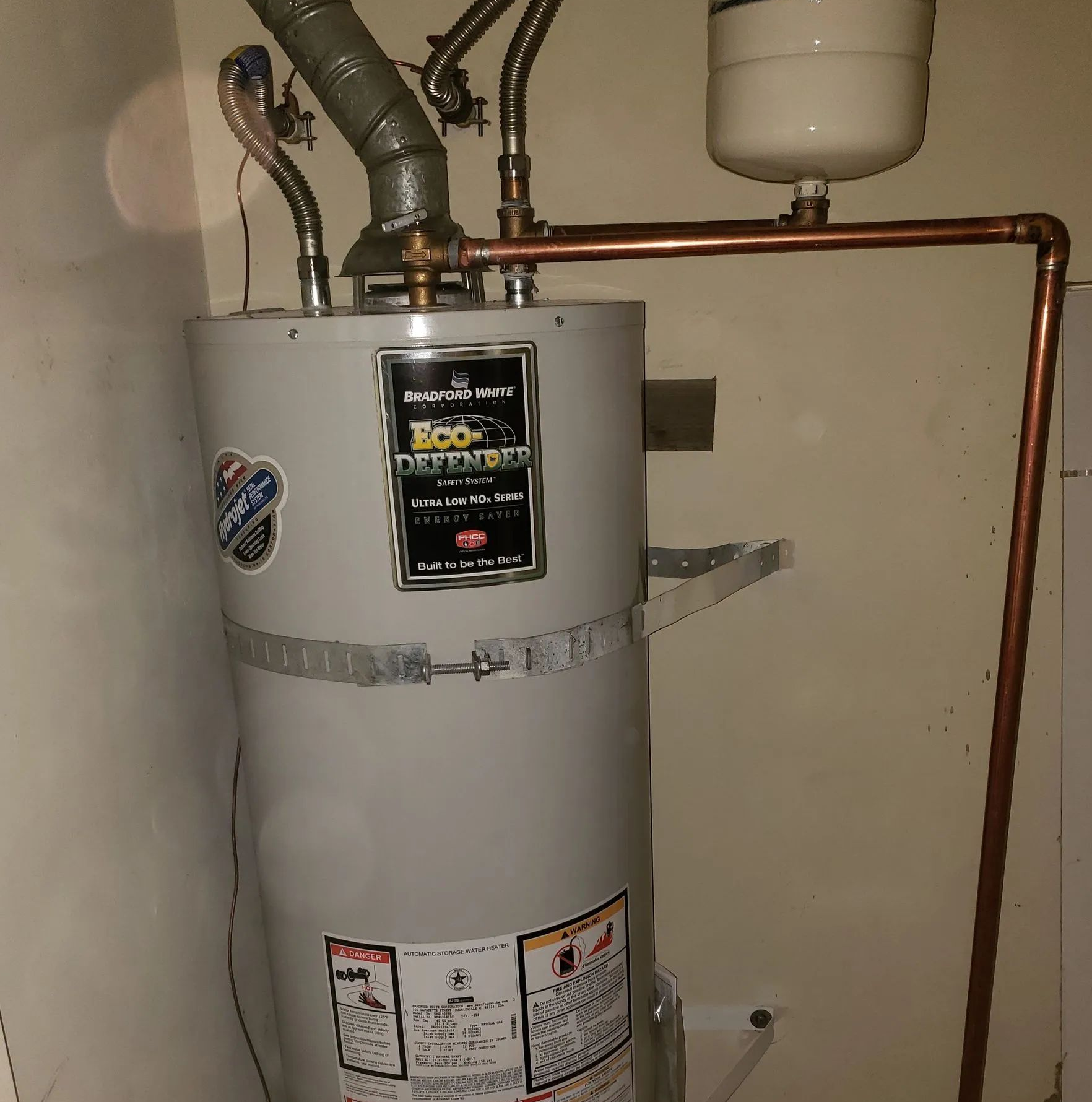 Water heater tank with copper piping and expansion tank in a utility room