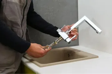 Person attaching a faucet adapter to a kitchen sink hose connection