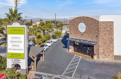 La Paloma Funeral Services building and sign on a sunny day with cars parked in the lot.