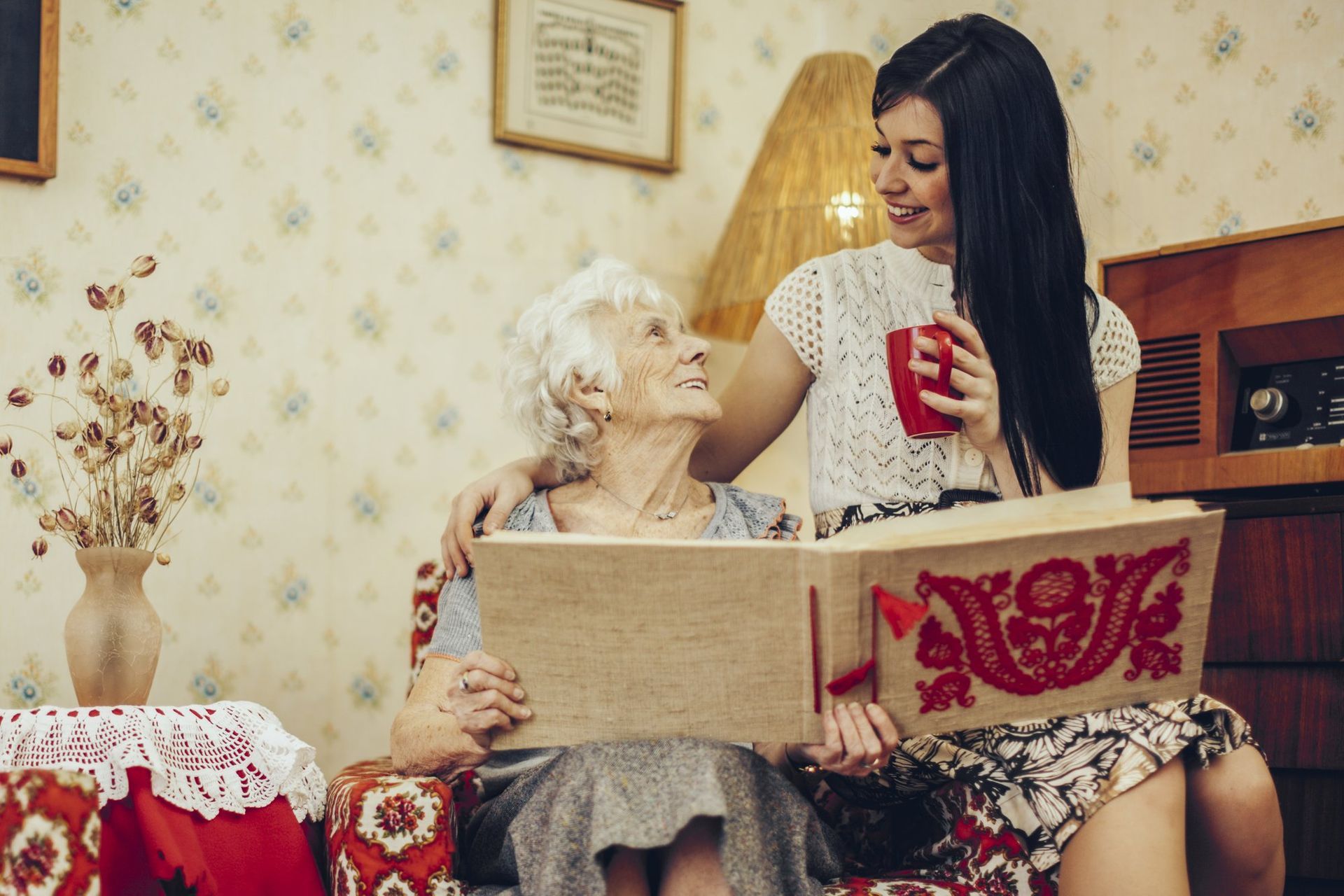 A young woman shares a warm moment with an elderly loved one while looking through a photo album