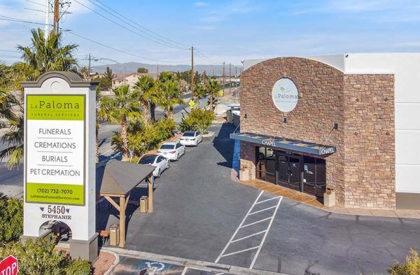 A single-story, tan, Mediterranean-style building named La Paloma Animal Hospital with a large parking lot in front.