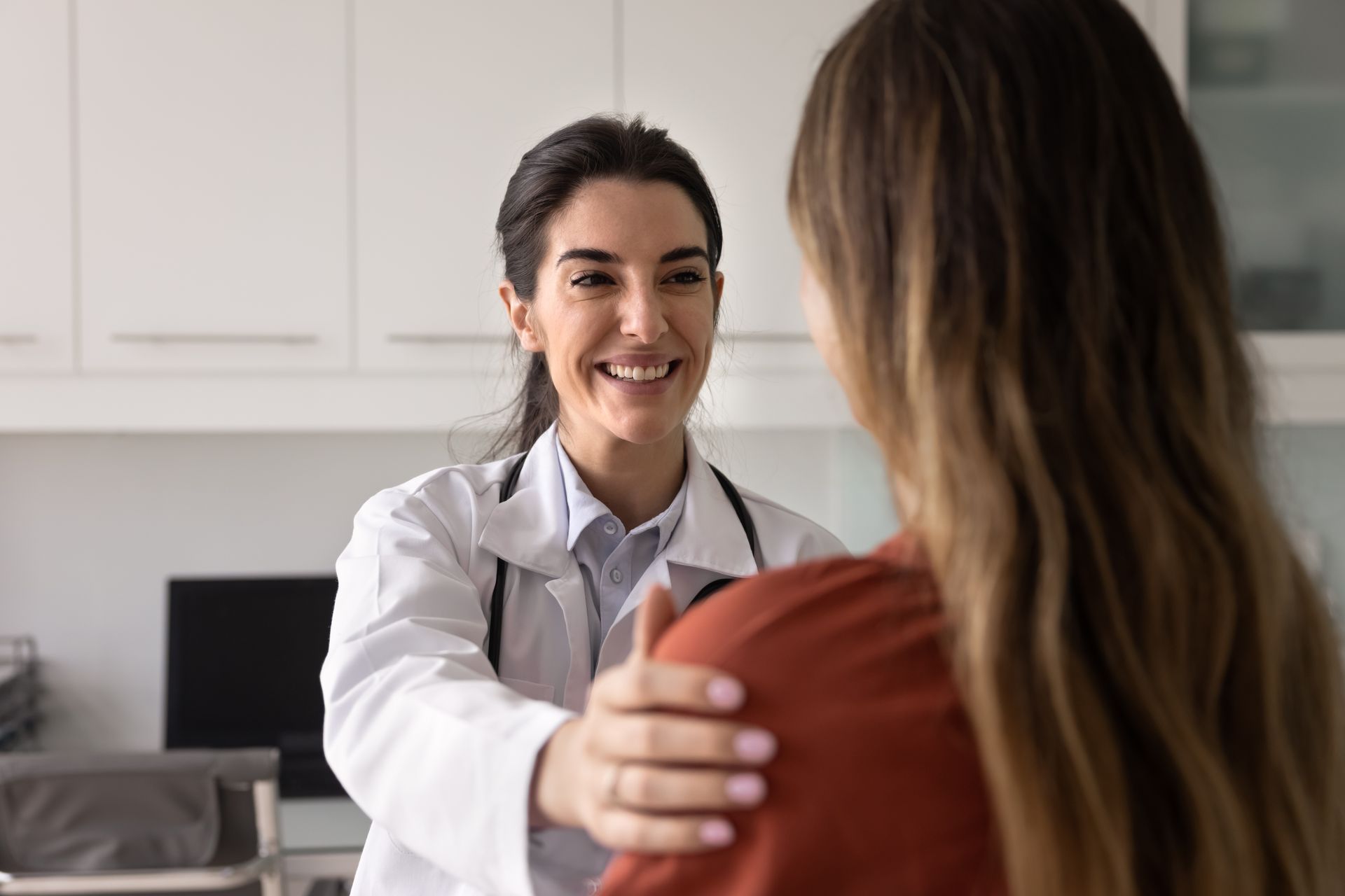 Doctor smiling and talking with a patient in a bright clinic office