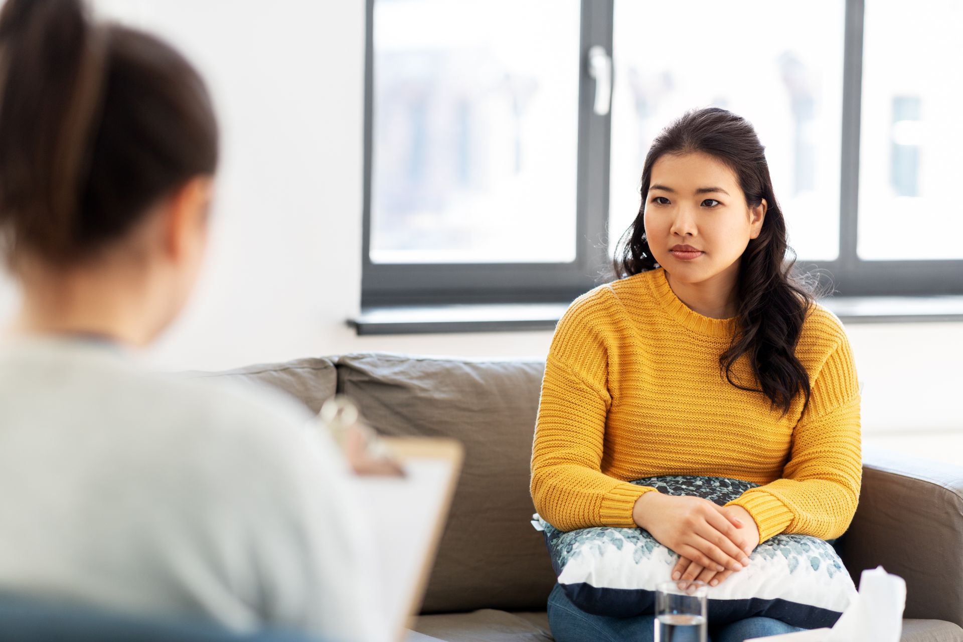 Woman in yellow sweater talking on a couch during a counseling session