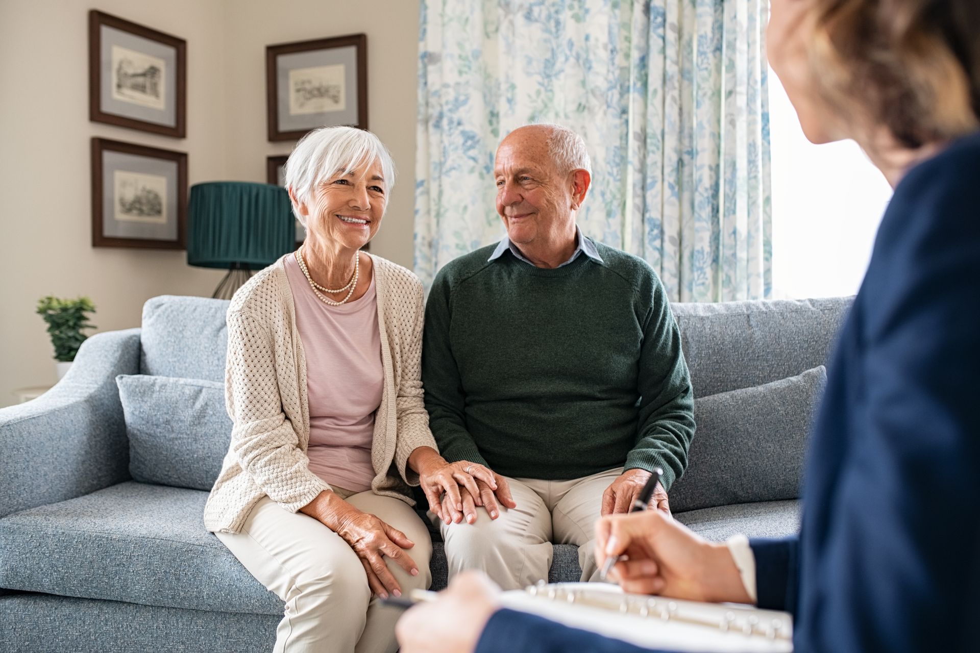 Counselor talking with two smiling clients on a sofa in a bright living room
