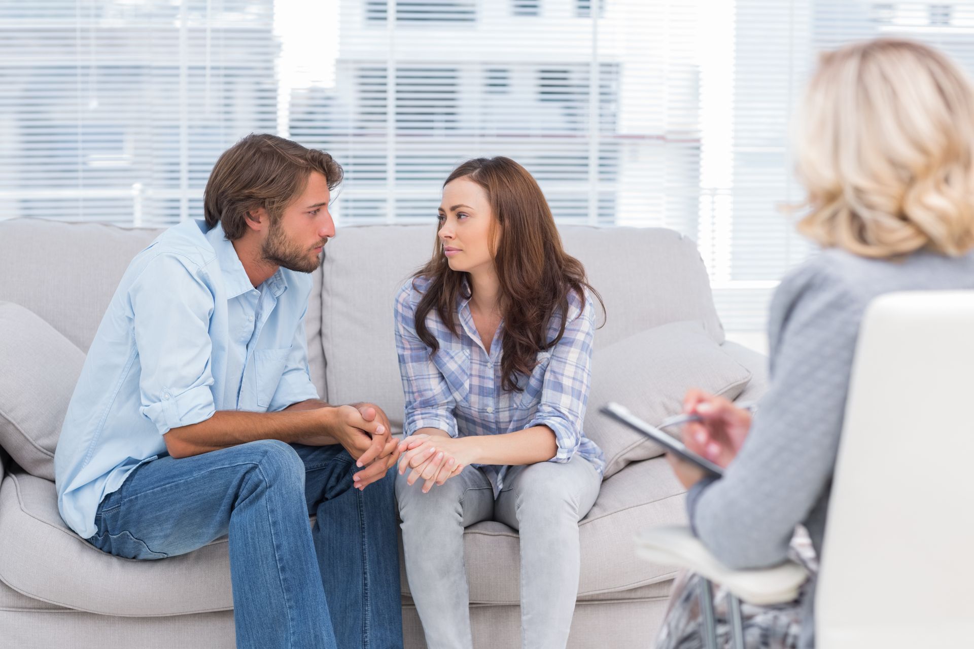 Two people talking on a couch with a counselor taking notes nearby