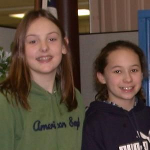 two girls are posing for a picture and one has an american boy sweatshirt on
