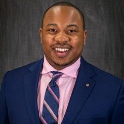 A man in a suit and tie is smiling for the camera.