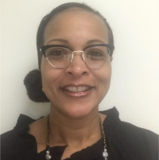 A woman wearing glasses and a black shirt is smiling for the camera.