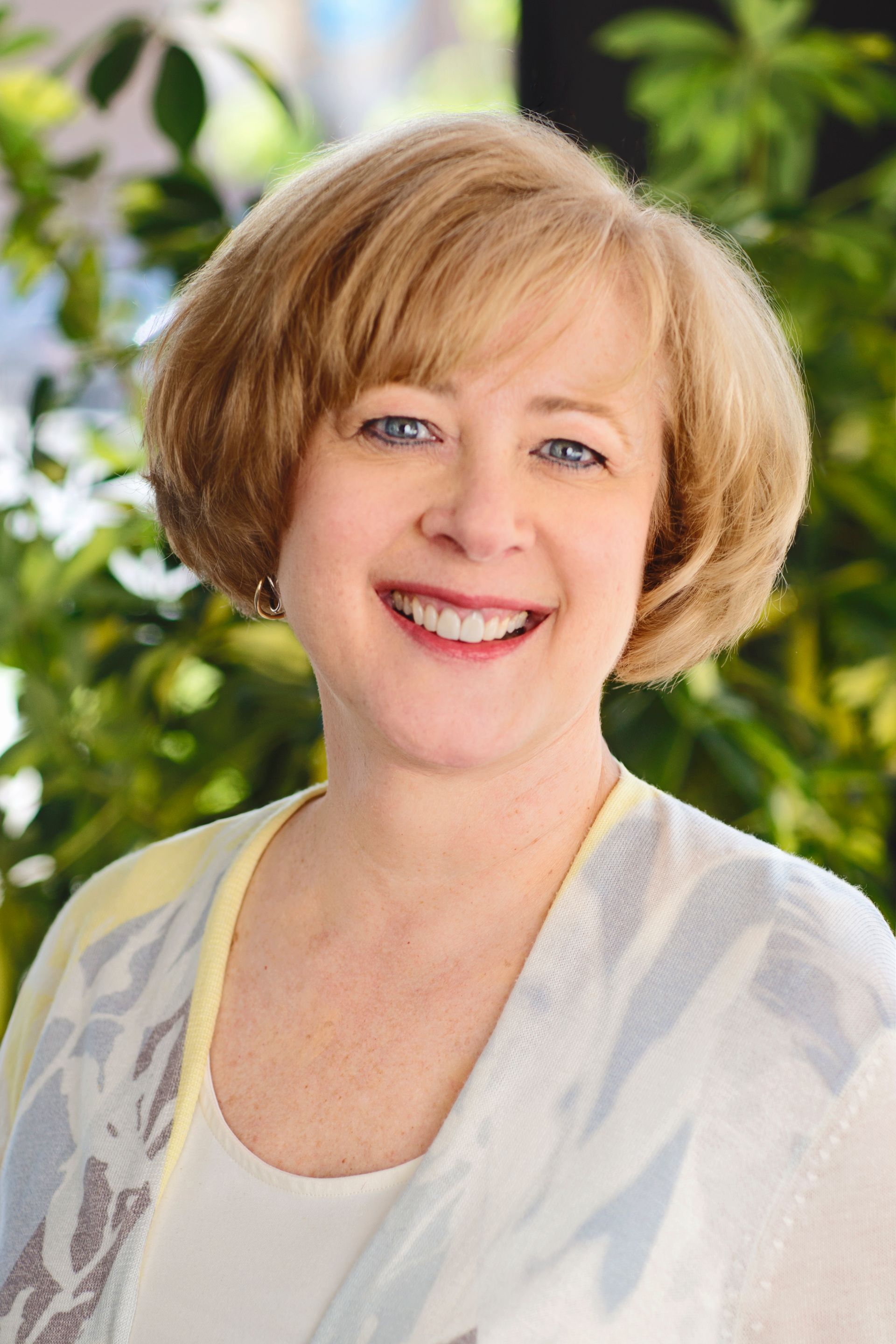 A woman with blonde hair and blue eyes is smiling for the camera.