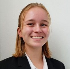 A young woman in a suit and white shirt is smiling for the camera.