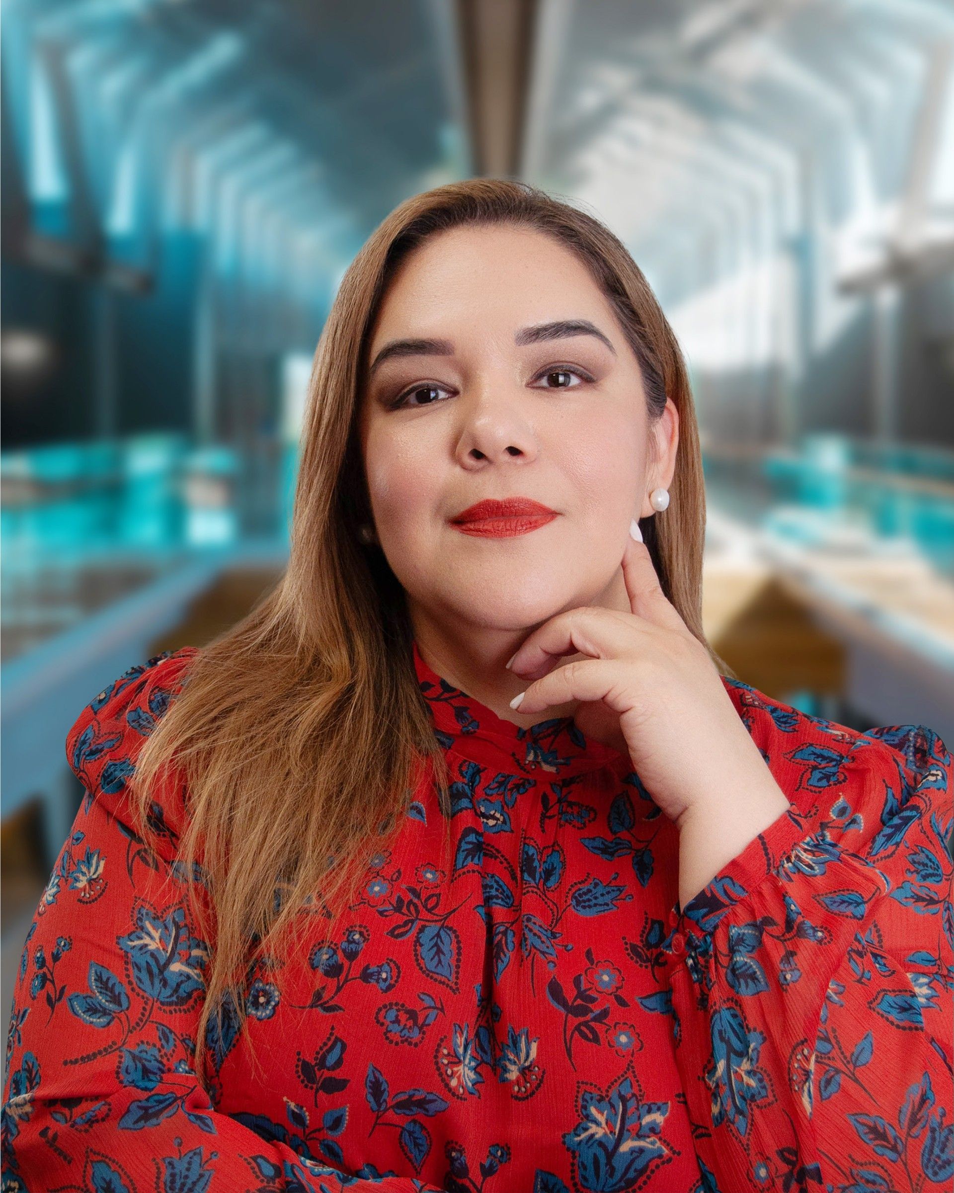 A woman in a red floral shirt is looking at the camera with her hand on her chin.