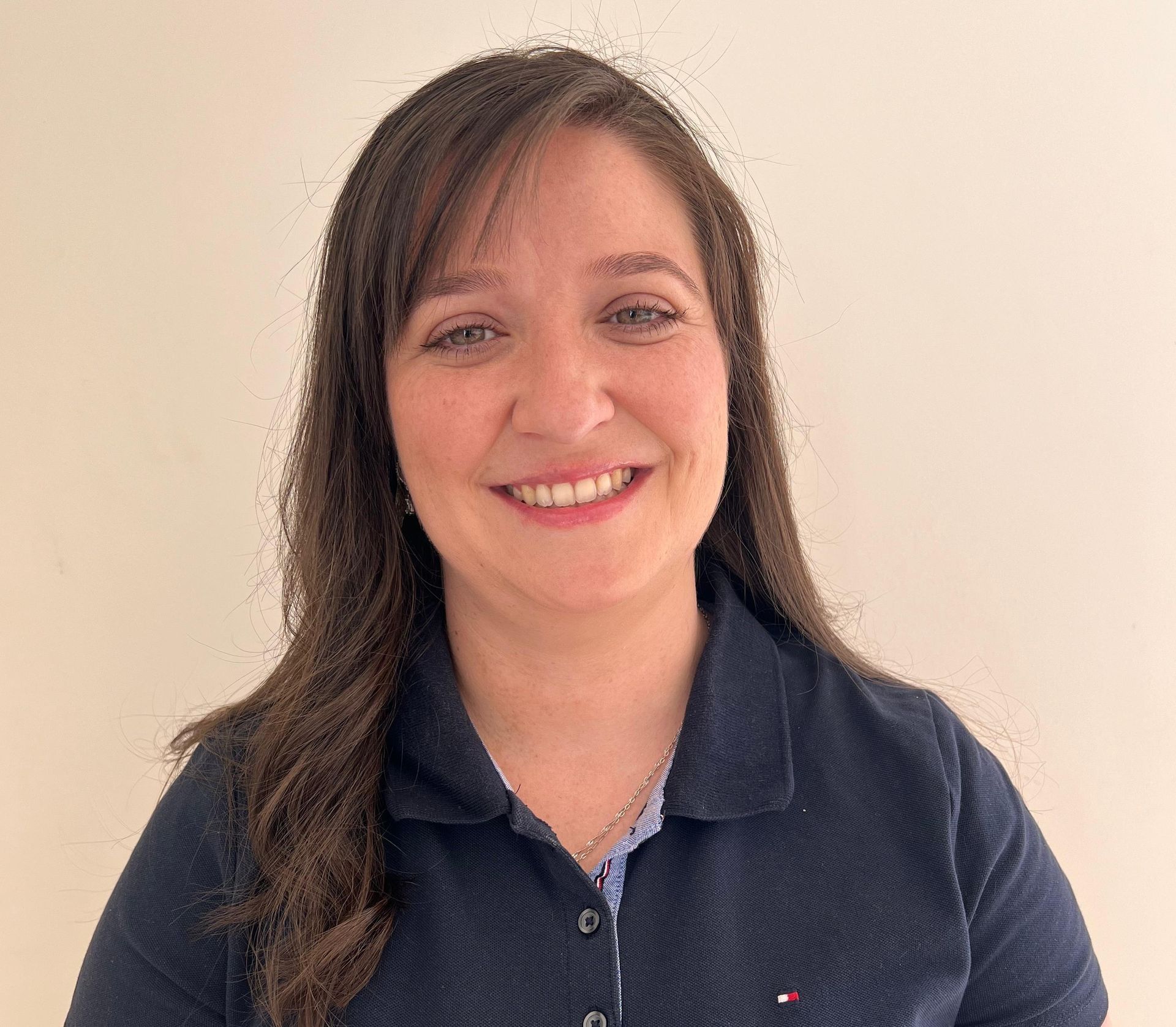 A woman in a blue polo shirt is smiling for the camera.