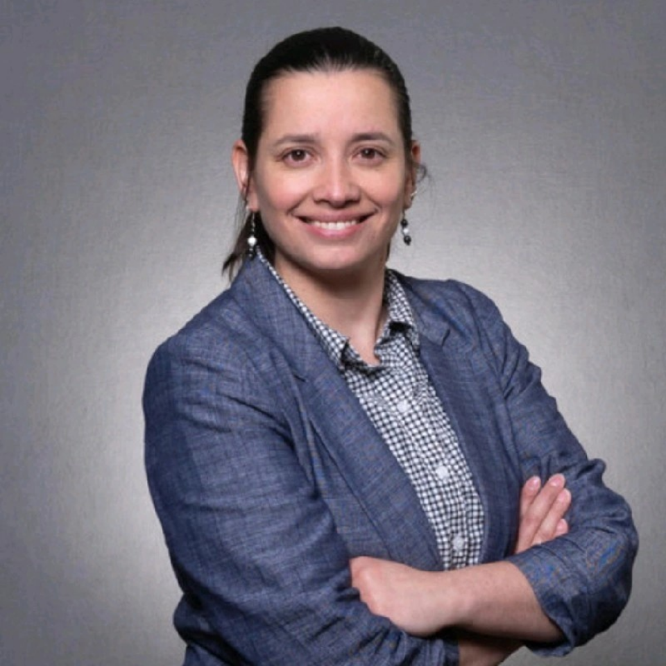 A woman in a blue polo shirt is smiling for the camera.