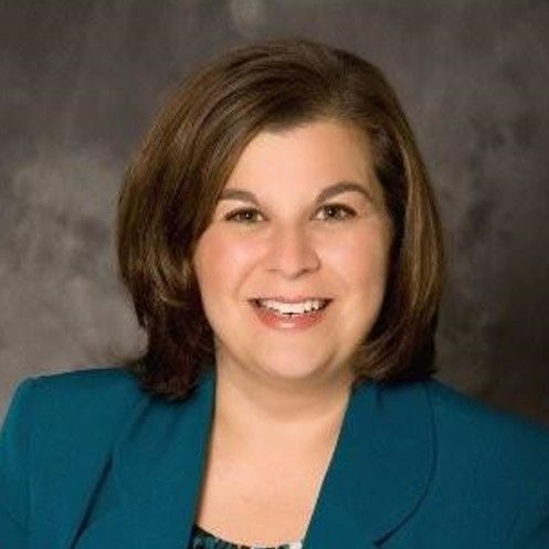 A woman in a blue jacket is smiling for the camera.