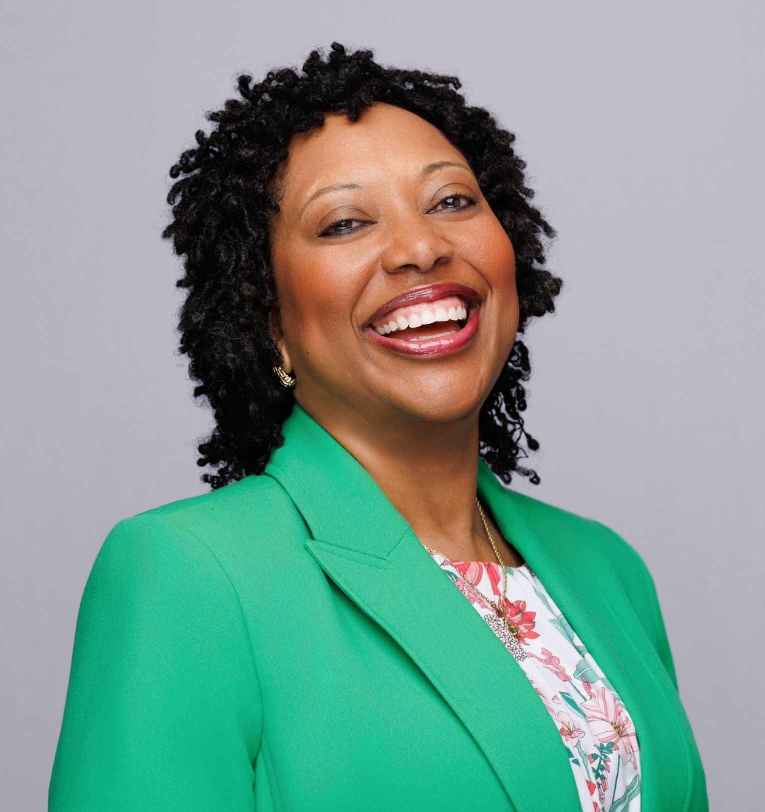 A woman wearing a maroon shirt and a necklace is smiling for the camera.